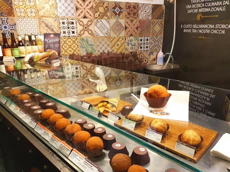 Arancini on display behind glass in a street food shop in Palermo