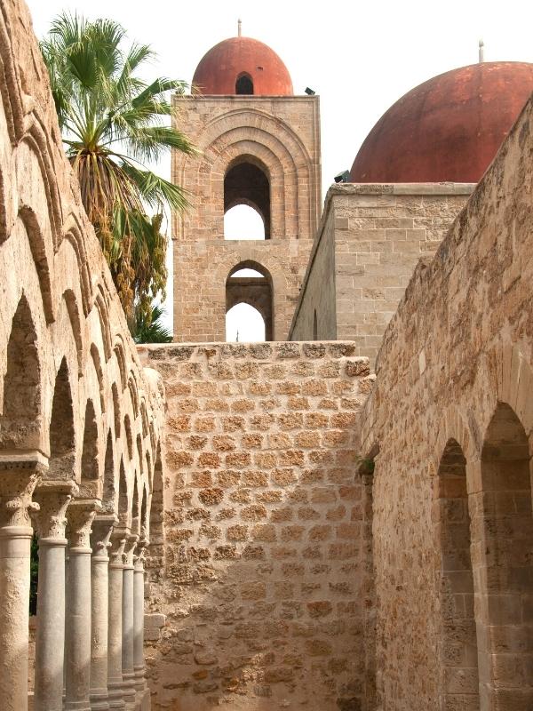 Historic building with arches and exposed brickwork and red comes towers