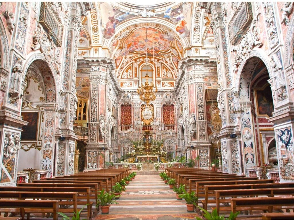 Very ornate church interior with painted relief plasterwork, ornate chandeliers and tiled floors