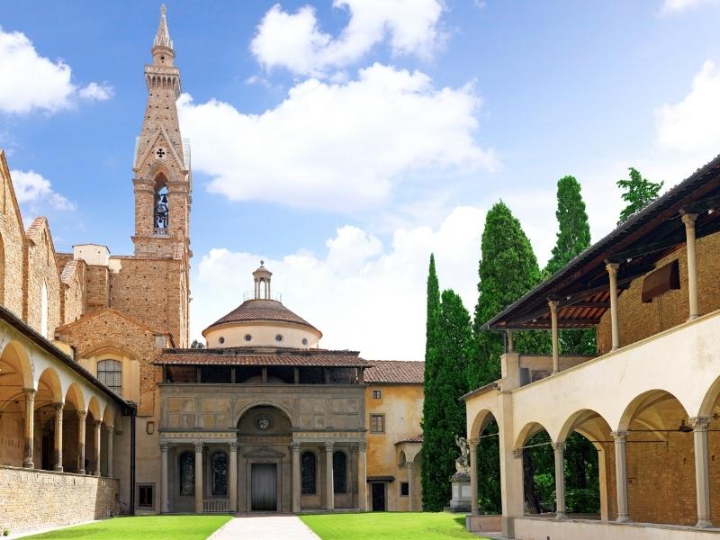 church cloisters with central grass and a bell tower in the background