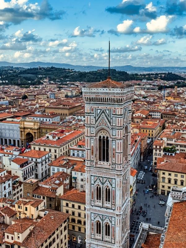 The skyline of Florence behind an ornate square bell tower