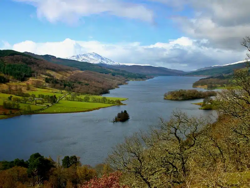 View down a body of water surrounded by forests to a snow capped mountains