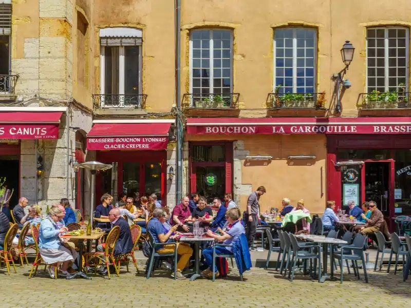 People sitting at tables outside a restaurant in a French city