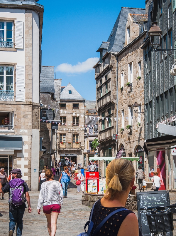 woman looking onto a lively street with shops, flags and people