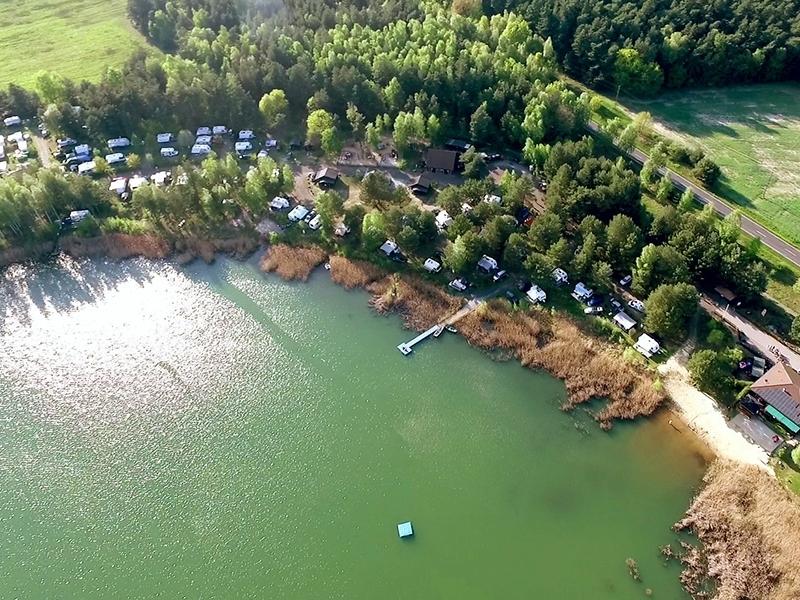motorhomes parked in a forest by a green lake