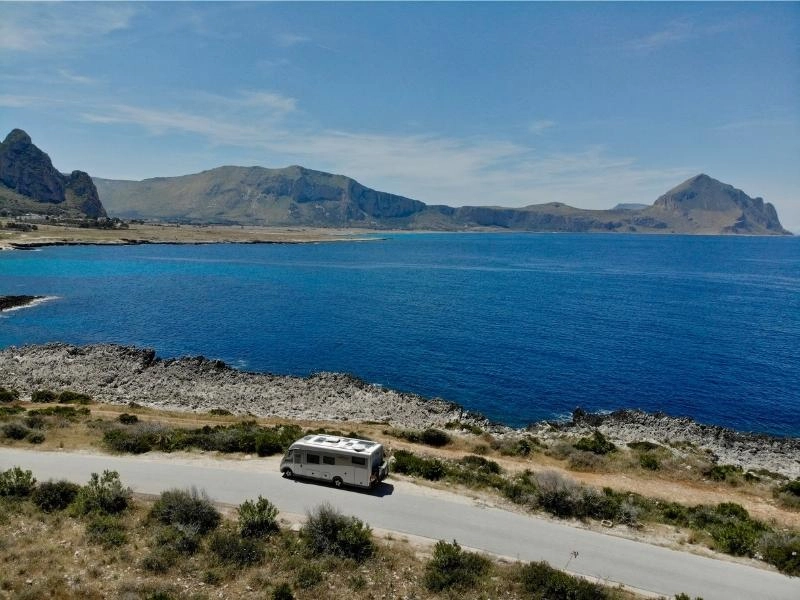 motorhome on a road by a large bay with deep blue water