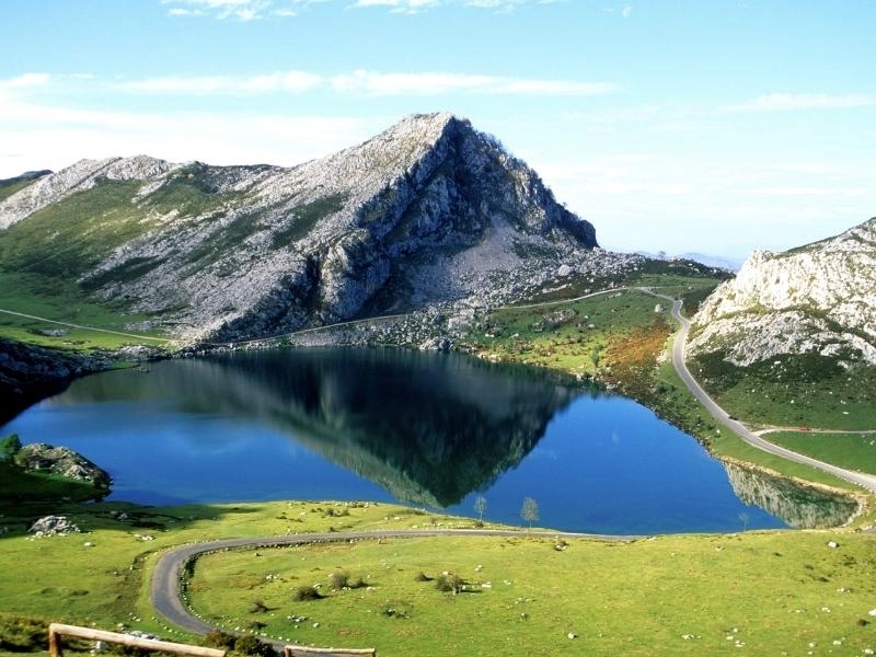 sweeping road through mountains and past a mirror lake in Spain