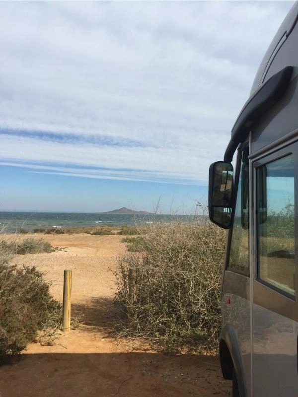 motorhome parked on the beach with a view of the sea and small island
