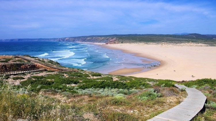 Large sandy bay with blue sea and a wooden boardwalk