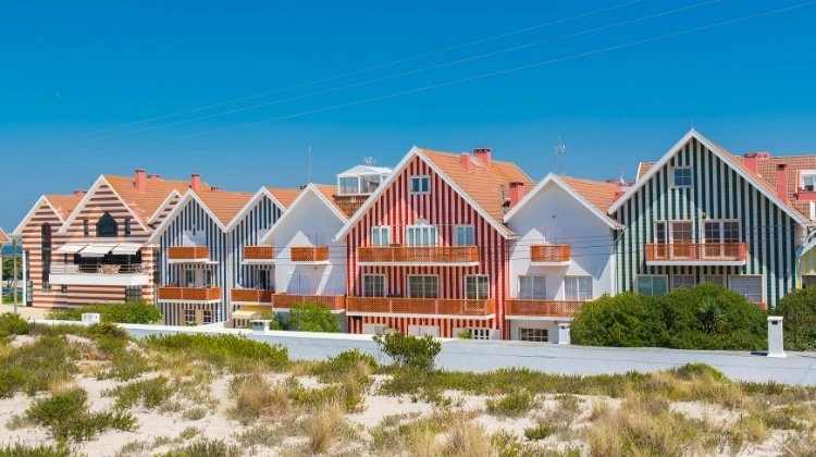 red, blue and white striped houses with small sand dunes in front