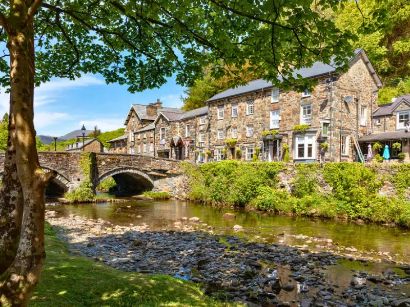 Attractive stone buildings beside a rocky river and stone arched bridge