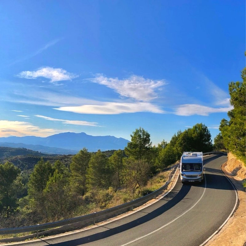 motorhome driving along a mountainous road surrounded by trees