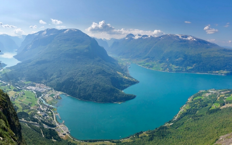 Turquoise fjord surrouned by wooden mountains topped with clouds