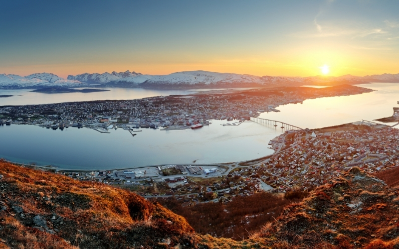 low level city on several islands with snow capped mountains in the distance