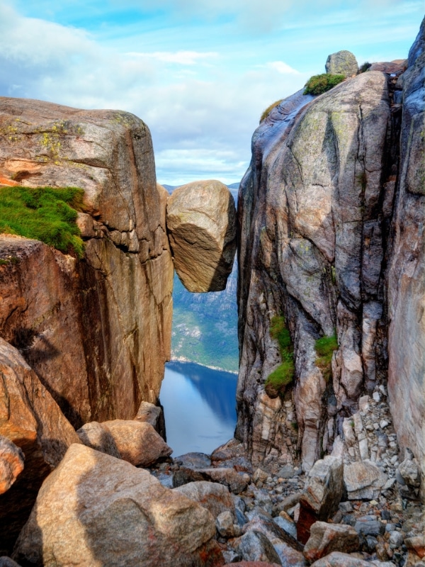 boulder trapped between two sheer cliff faces above a fjord in Norway