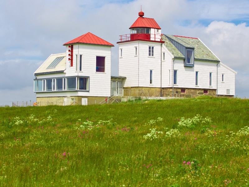 white wood lighthouse and other buildings with red roofs