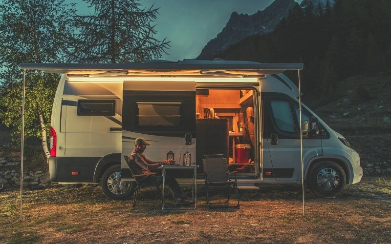 campervan parked up with sliding side door open and lights on