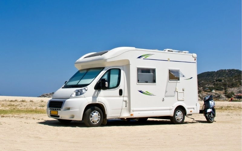 low profile motorhome parked on a beach with a scooter