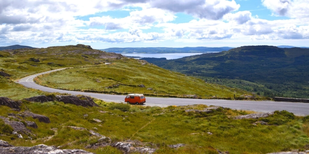 red campervan on a road with Irish mountains in the background