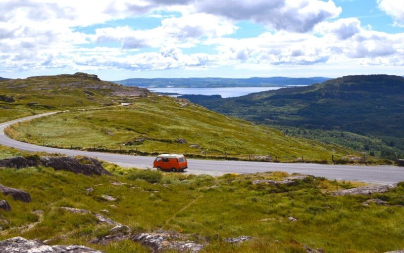 red campervan on a road with Irish mountains in the background