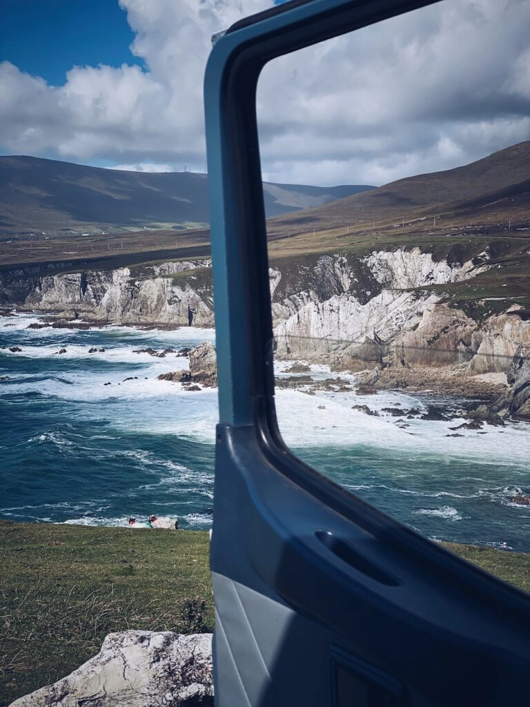 View of dramatic white cliffs and green fields through a campervan window