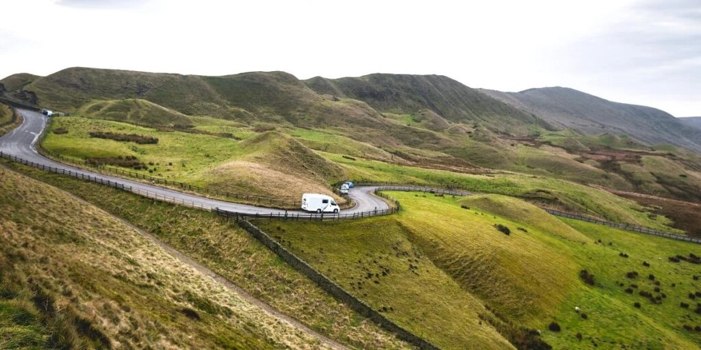 motorhome driving on a road through green mountains in Wales