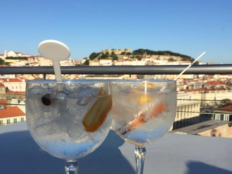 tow large drinks with ice and orange sliced in a table with a castle in the background