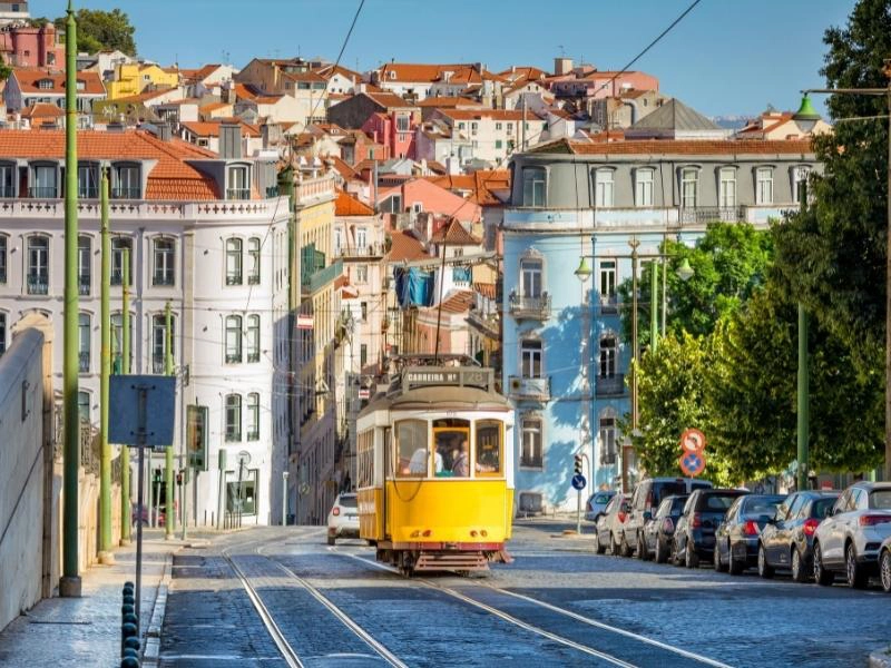 lisbon yellow tram on a hill of pastel colored houses