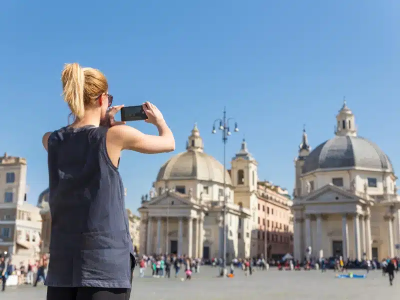 female tourist taking a photo of a Roman church on a smartphone