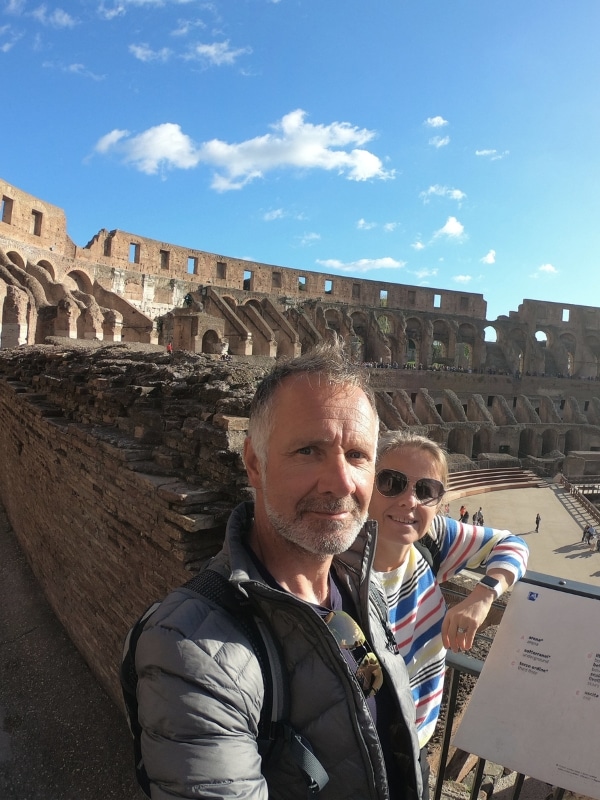 couple standing in the Colosseum with brick walls and seating areas behind them