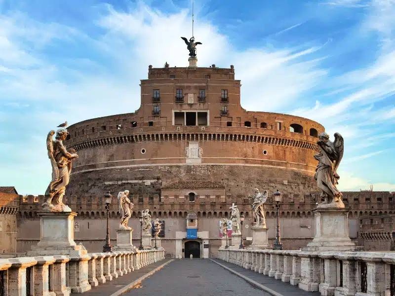  large circular castle seen over a bridge lined with statues