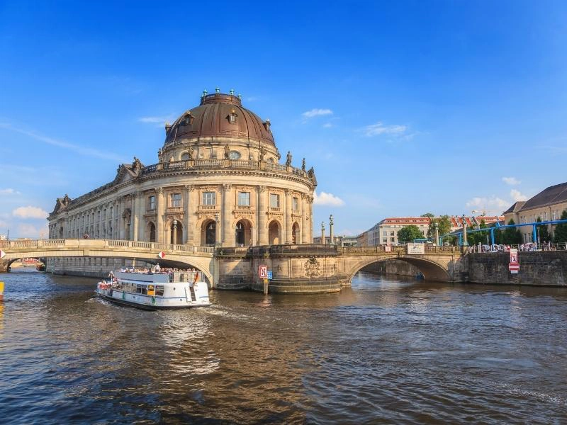 A boat on a tiver by and ornate round building in Berlin