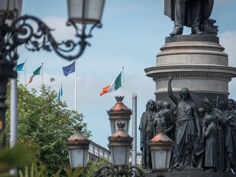 Statue and street lights with tricolour orange white and green flag of the Republic of Ireland flying