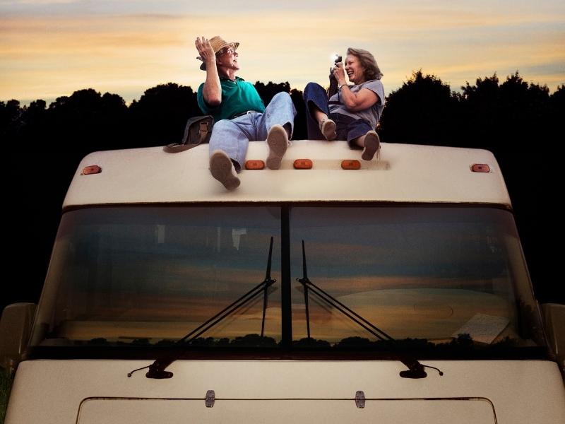 two people on top of a motorhome taking photos
