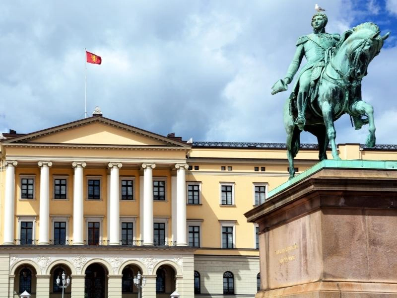 elegant stone building with pillars and a green copper statue of a man on a horse in the foreground