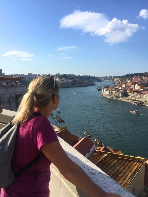 woman in a pink t-shirt looking at a city and river from a viewing point