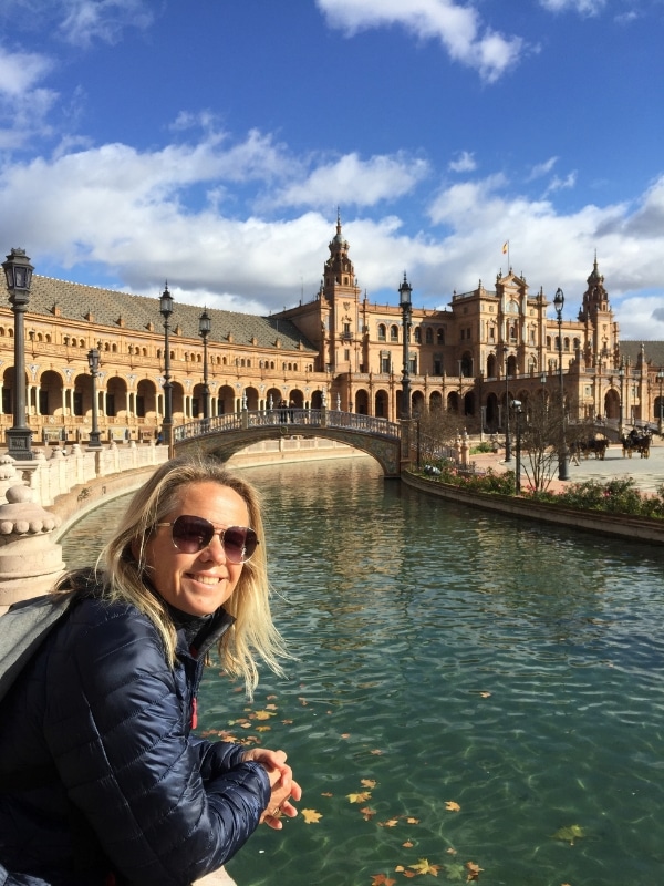 woman looking at an ornate river with a bridge in front of historical buildings