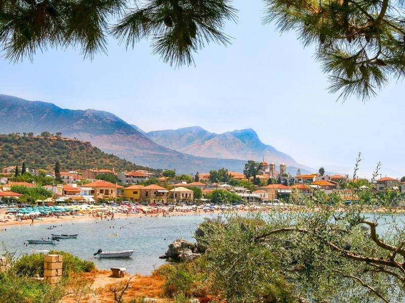 Busy beach with sun shades and mountains behind