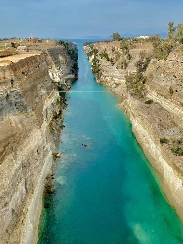 bright turquoise canal lined with steep cliffs and the open sea in the distance