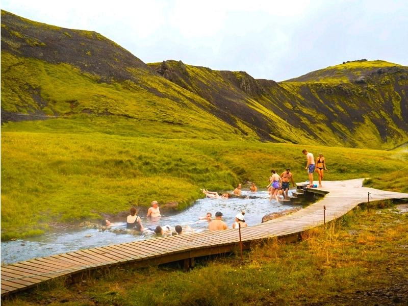 wooden boardwalk along hot springs where people are bathing