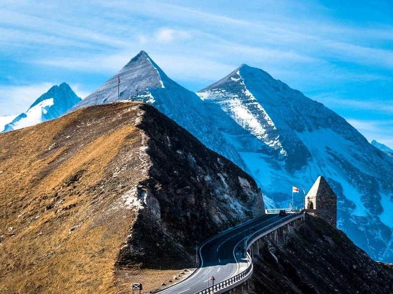 Road through a high alpine pass with snow on surrounding mountains