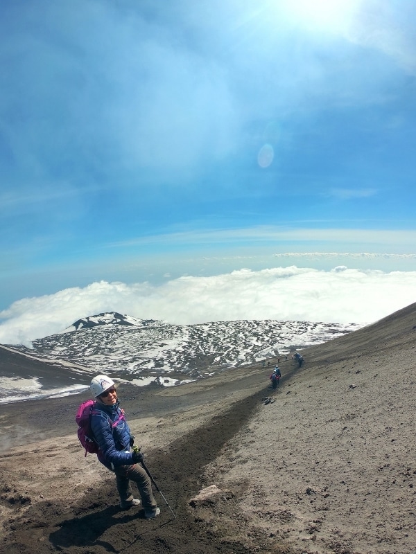 Woman at the top of an ashy hill above the clouds