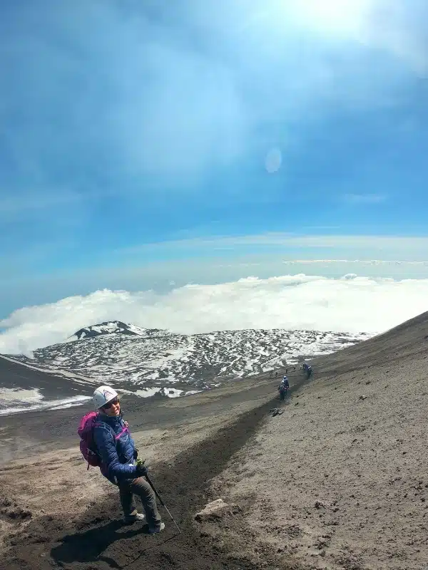 Woman at the top of an ashy hill above the clouds