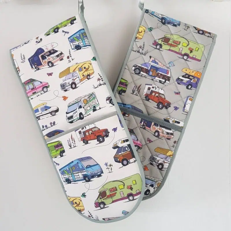 An image of oven gloves, s pairs one grey and one white with images of different motorhomes on them