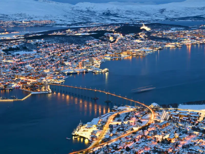 A snow covered Arctic city along the banks of a wide river with a modern bridge connecting them