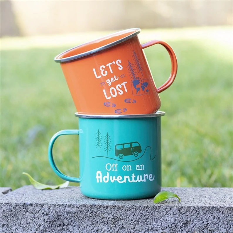 Image showing two enamel mugs one green with the words Off on an Adventure & and one orange with the words Lets get Lost 