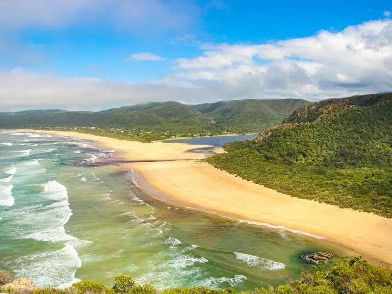 Sandy beach and inlste with tree covered hills on either side