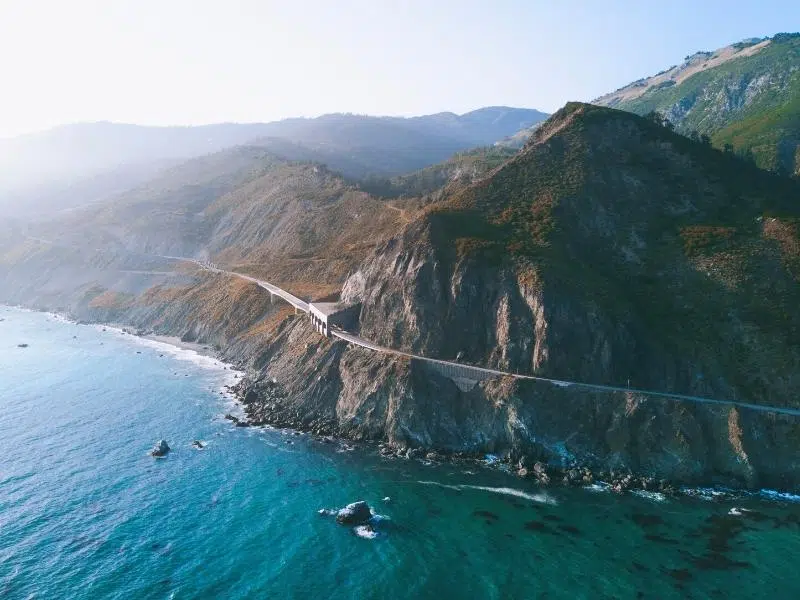 Road along a cliff by the ocean with mountains inland