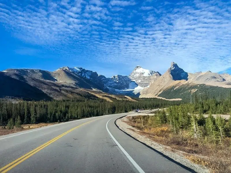 Road heading into small snow capped mountains