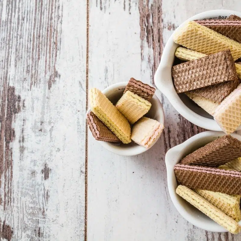 A whitewashed table top with 3 bowls filled with wafer biscuits